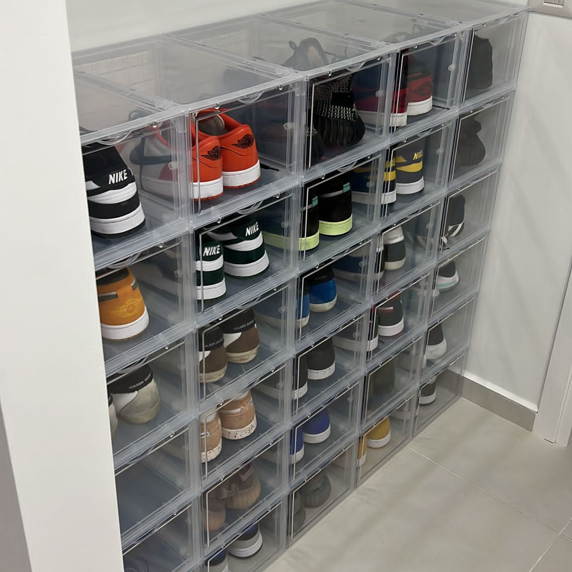 Clear shoe storage boxes with shoes inside in a room.